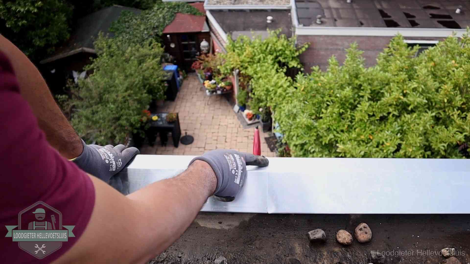 Daklekkage geregeld in Hellevoetsluis Vakman plaatst een daktrim op de dakrand van een woning in Hellevoetsluis