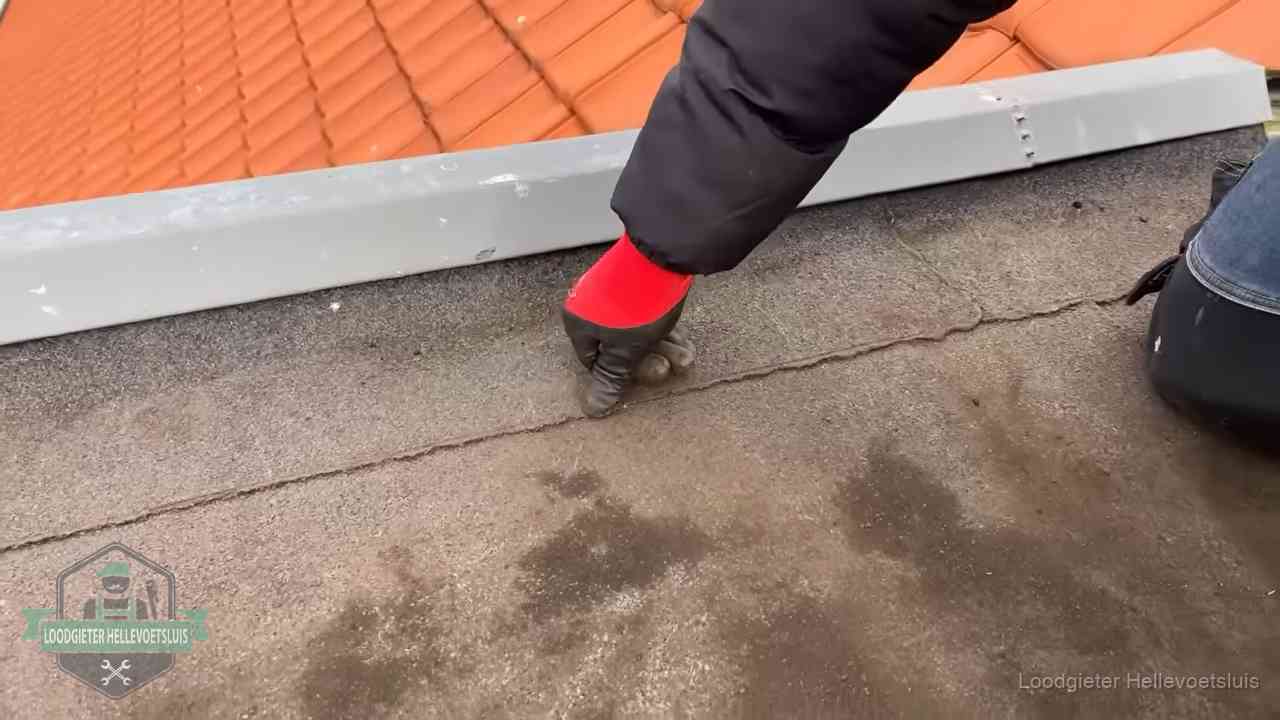 Lekkage bij de naad van een plat dak in Hellevoetsluis Vakman wijst een naad met vochtplekken aan op een bitumen plat dak in Hellevoetsluis