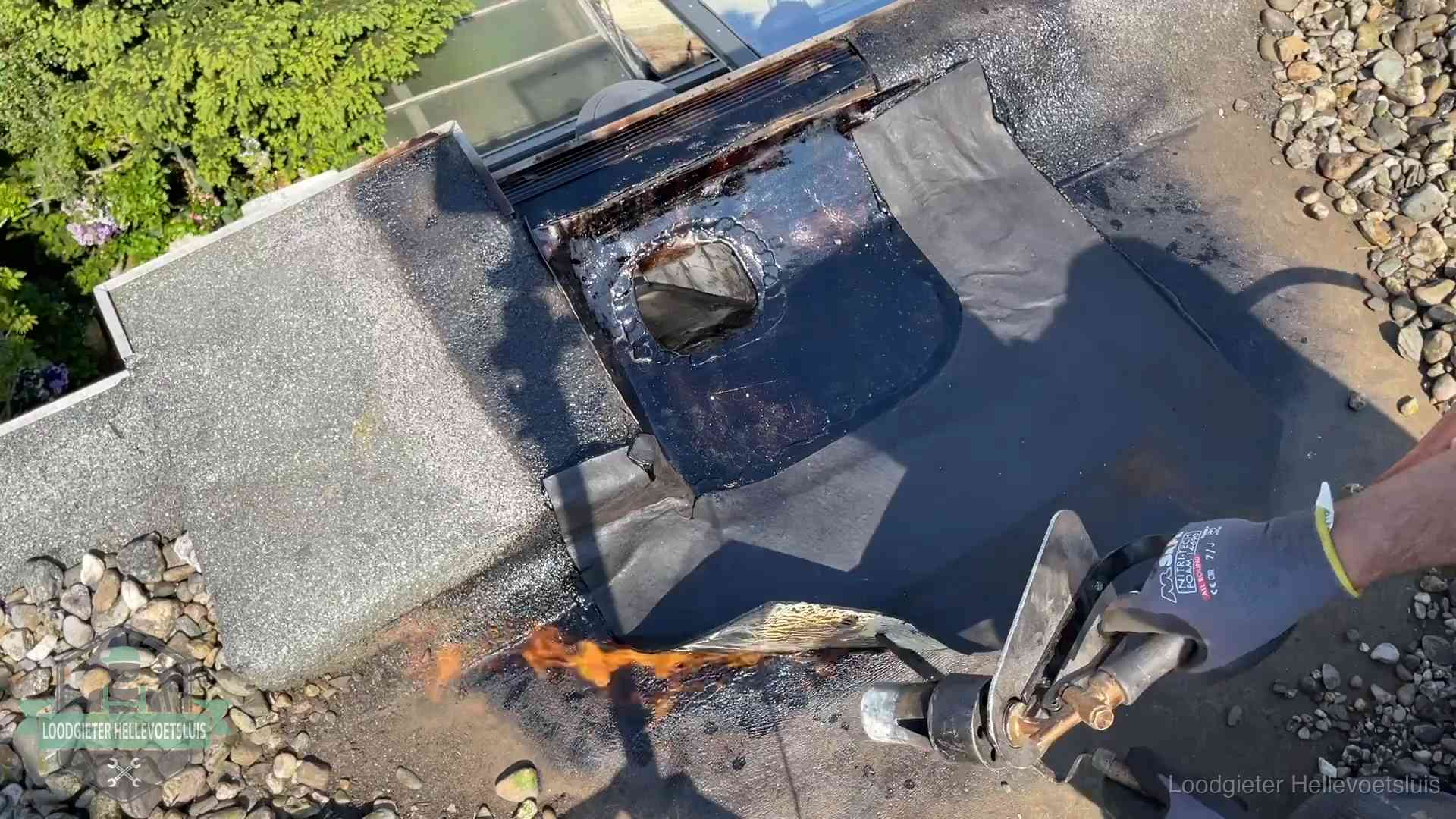 Daklekkage repareren in Hellevoetsluis Dakdekker brandt bitumen rond een doorvoer tijdens een daklekkage-reparatie in Hellevoetsluis