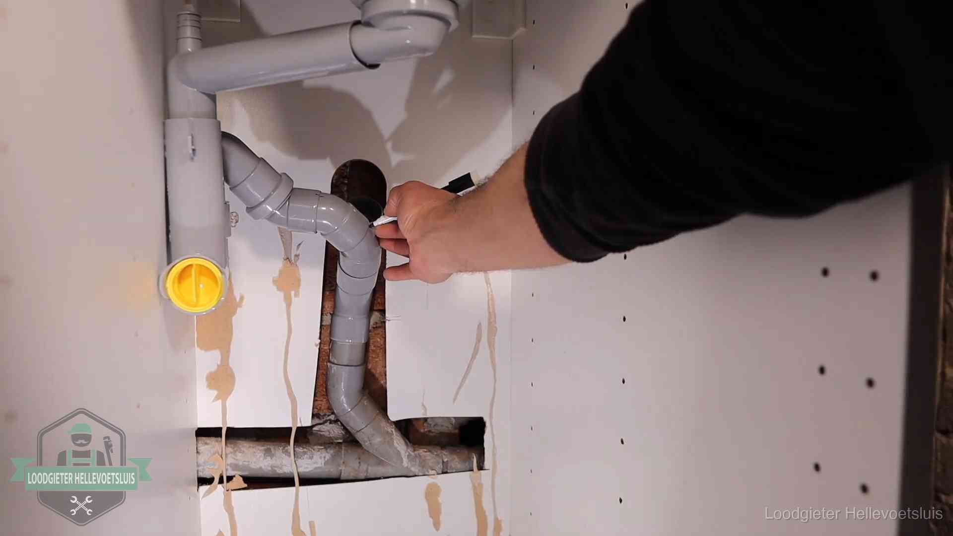 Loodgieter voor verhuurders en bedrijven in Hellevoetsluis Loodgieter markeert een pvc-afvoerbuis onder een gootsteen in Hellevoetsluis