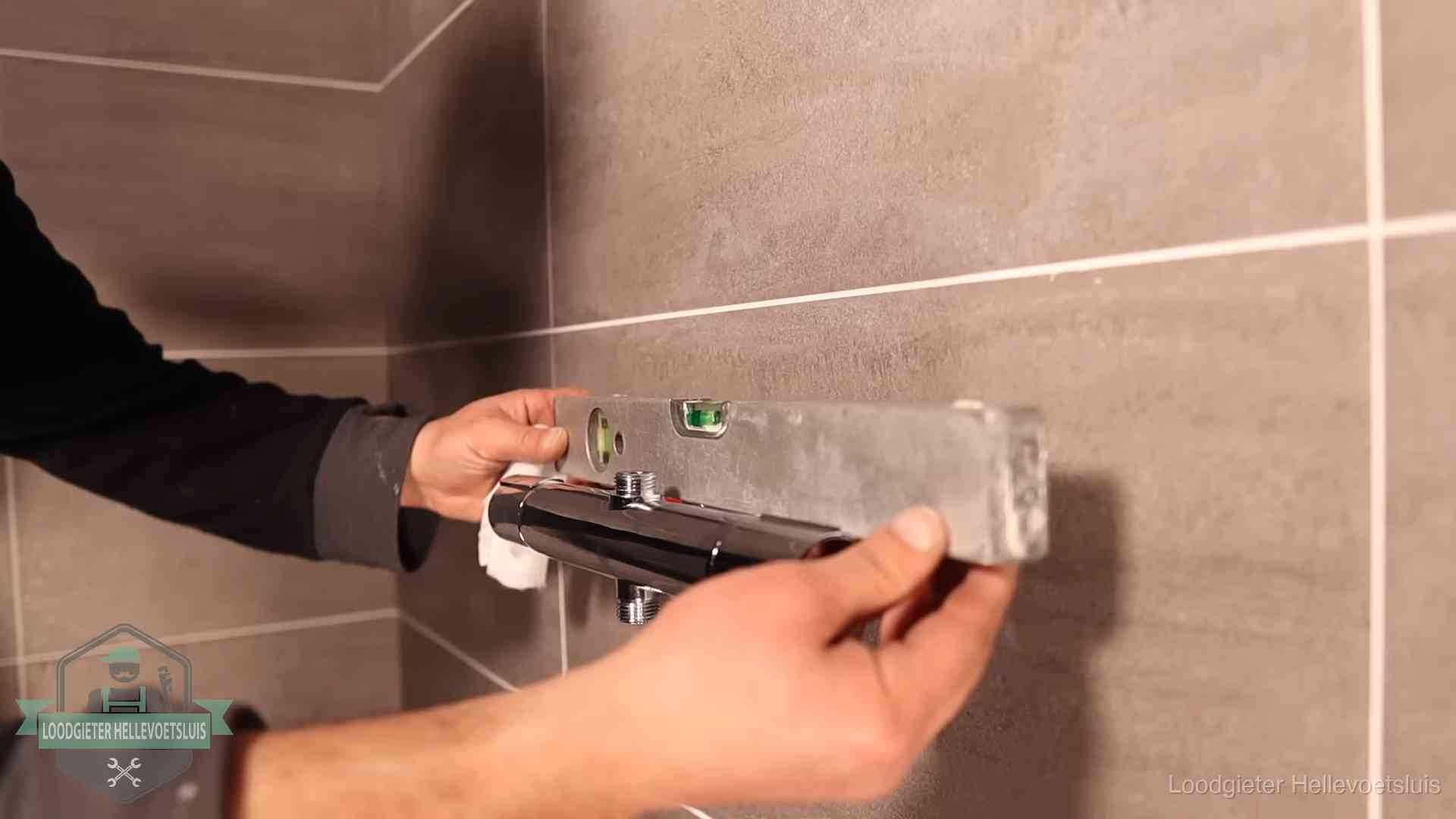 Loodgietersbedrijf voor sanitair in Hellevoetsluis Loodgieter lijnt een douchekraan uit met een waterpas in een woning in Hellevoetsluis